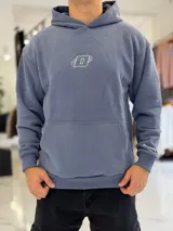 Canguro oversize de color azul, con capucha, bolsillo frontal tipo canguro y diseño bordado en el pecho. Cuenta con puños y cintura elastizados.