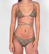 Conjunto de bikini verde con estampado de cuadros y corazones rojos. El corpiño es de triángulo con breteles finos y tiras largas para atar al torso. La bombacha es tipo tanga con tiras laterales ajustables.
