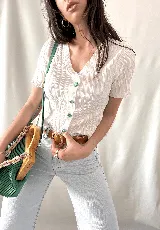 Camisa blanca con textura arrugada, escote en V, mangas cortas con volados y botones con forma de flor.