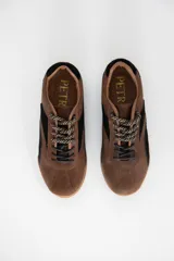 Zapatillas urbanas de cuero, combinando paneles en color camel y negro, con suela de goma color caramelo y cordones jaspeados.