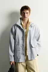 Parka relaxed fit de algodón con efecto lavado, color gris, cuello subido, manga larga y bolsillos de plastrón con solapa en el delantero. Cuenta con cierre frontal de botones y solapa.