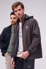Campera repelente al agua y cortaviento color marrón oscuro, con capucha desmontable y cierre frontal. Cuenta con bolsillos y puños elastizados, además de un parche redondo en el pecho.