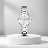 Reloj analógico de mujer con caja redonda y malla de eslabones metálicos en color plateado. Presenta esfera minimalista con índices finos y movimiento de cuarzo japonés.