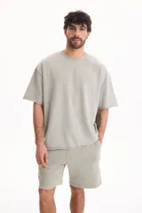Remera oversize gris oscuro con efecto lavado, cuello redondo y mangas cortas amplias.