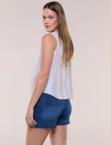 Blusa sin mangas de algodón liviano con diseño de rayas verticales en tonos beige y blanco, escote redondo, abotonadura frontal con botones rústicos y detalle de nudo para anudar en la cintura.