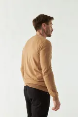 Sweater de punto color rosa con cuello en V y logo bordado en el pecho.