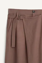 Pantalón de corte relajado confeccionado en tejido fluido con mezcla de viscosa y lino. Presenta un diseño cruzado en la cintura con cierre de cremallera, botón y trabilla ajustable. Cuenta con bolsillos laterales y bolsillos traseros de vivo con botón.