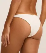 Bikini bottom confeccionada en microfibra color crema, con cintura contrastante color marrón y detalle de medalla aplicada.