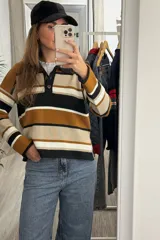 Sweater de punto con diseño a rayas horizontales en tonos negro, beige y mostaza. Presenta cuello tipo polo con cierre de botones, mangas largas y corte holgado.