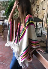 Chal tejido a mano en lana merino, con diseño de jacquard geométrico multicolor a rayas en tonos crudo, fucsia, verde, amarillo y marrón, terminado con flecos en los extremos.