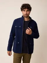 Campera de estilo safari en color azul marino, confeccionada en algodón. Presenta cuello alto, cierre frontal con cremallera y cuatro bolsillos delanteros con solapa y botones metálicos.