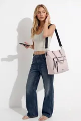 Cartera shopper rosada con doble bolsillo frontal con cierre, asas cortas de mano y correa larga ajustable de cinta negra.