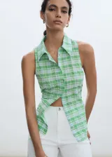 Camisa sin mangas de corte recto, confeccionada en tejido mezcla de algodón con estampado de cuadros en tonos verdes y celestes. Presenta cuello camisero y cierre frontal con botones.
