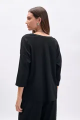 Remera negra de manga tres cuartos, corte oversize y textura acanalada.