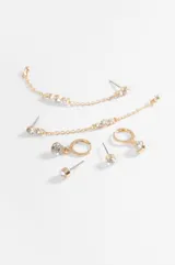 Set de tres pares de caravanas doradas con incrustaciones de strass. Incluye un par de abridores pequeños, un par de argollas con dije colgante y un par de caravanas largas con cadena y detalles de cristales.