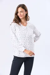 Blusa de manga larga con cuello redondo y cierre frontal de botones. Presenta un estampado floral en color negro sobre fondo blanco.
