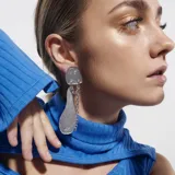 Aros colgantes plateados con diseño geométrico y textura brillante.