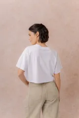 Remera crop color beige, de calce amplio, escote redondo y mangas cortas sueltas.