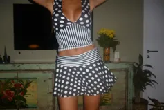 Falda corta de modal y lycra con diseño estampado de lunares blancos sobre fondo negro y detalle de franja a rayas horizontales en la cintura.