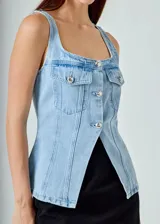 Chaleco de jean celeste con corte ajustado, cuello cuadrado, cierre frontal con botones metálicos y bolsillos de parche en el pecho.