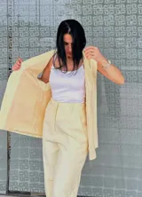 Pantalón de vestir amarillo con finas rayas verticales blancas, corte recto, tiro alto y bolsillos laterales.