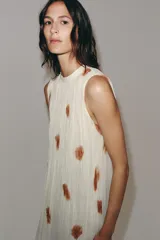 Vestido midi de viscosa color blanco con estampado abstracto marrón, diseño sin mangas, cuello redondo plisado y cierre de lazos en la espalda.