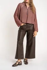 Sweater marrón de punto acanalado, con cuello alto, cierre frontal parcial con cremallera y manga larga.