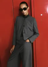 Blazer cropped gris de cuello redondo y manga larga, con patrón de cuadros, bolsillos de ribete delanteros y cierre de botones.