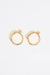 Par de aros de metal dorado con forma de aro grueso y textura irregular.