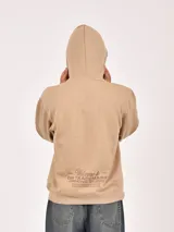 Hoodie color beige con capucha y bolsillo canguro frontal. Presenta un estampado minimalista en color marrón en el pecho con texto que incluye "GR Trademark", "Unfiltered Content" y "worldwide".