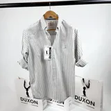 Camisa de manga larga a rayas verticales grises y blancas, con cuello italiano y logo bordado en el pecho.