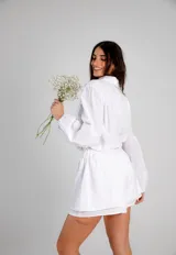 Conjunto de dos piezas confeccionado en lino color blanco. Incluye una camisa de corte holgado con mangas abullonadas y bolsillos frontales, y un short de tiro alto con cintura elástica y forro interior.