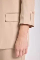 Blazer de color visón con mangas tres cuartos, solapas clásicas y cierre frontal con un botón. Presenta bolsillos laterales con solapa.