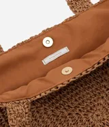 Bolso de playa tejido en fibra de papel color marrón claro, con asas medianas y detalle de logo metálico dorado en el centro.