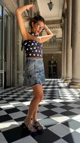 Falda corta de denim con lavado ácido (acid wash) y ruedo desflecado. Presenta un corte acampanado y cierre metálico en el costado.