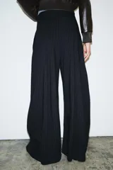Pantalón de tiro medio con diseño de raya diplomática, corte wide leg y detalle de pinzas en el delantero. Cuenta con cintura con trabillas, bolsillos laterales y cierre frontal con cremallera, botón y ganchos metálicos.
