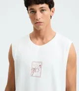 Musculosa blanca de algodón, de corte comfort y cuello redondo. Presenta un estampado localizado en el pecho con un diseño de palmeras y un atardecer en tonos rosados y naranjas.