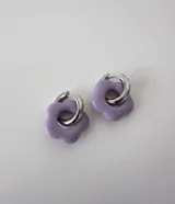 Aros de acero quirúrgico con argolla plateada y dije de flor translúcida en color lila con lunares negros.