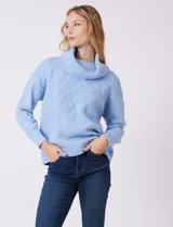 Buzo de punto grueso con textura en relieve, de cuello volcado y mangas largas con hombros caídos. Presenta puños y ruedo con terminación en rib.