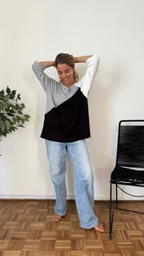 Remerón de manga tres cuartos con diseño de bloques de color en diagonal: gris claro en la parte superior izquierda, negro en la parte inferior derecha y blanco en la manga derecha. Posee cuello redondo y calce holgado.