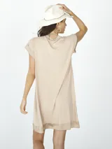 Vestido corto color beige, de tricot con terminaciones de razo y escote en V.