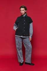 Chaleco de jean oversized color negro, con cuello camisero y cierre frontal con botones metálicos. Presenta un diseño estructurado con costuras reforzadas.