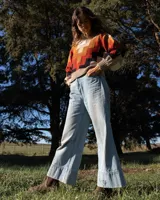 Buzo de tejido de punto con cuello alto y diseño geométrico en zigzag. Presenta una combinación de colores cálidos como naranja, rojo, negro y beige, con puños y cintura acanalados.