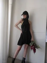 Vestido mini negro de microfibra liviana con escote halter y espalda semi descubierta. Silueta entallada al cuerpo con ballenas.