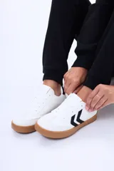 Championes urbanos de estilo retro, color blanco con detalles en negro en los laterales y suela de goma color caramelo.