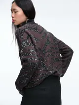 Cardigan de punto con escote en V y cierre frontal de botones. Presenta un diseño estampado de animal print con acabado brillante, mangas largas y corte holgado.