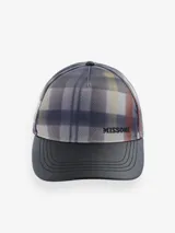 Gorro estilo trucker o beisbol con visera estructurada. La corona presenta un estampado de zigzag o chevron en tonos azules, grises, amarillos y rojizos, característico de Missoni. El logo "MISSONI" está bordado en negro en la parte frontal. La visera es de color negro liso, posiblemente de cuero sintético.
