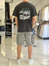 Remera oversize negra con efecto gastado, de manga corta, con estampa en la espalda que incluye texto y la ilustración de un auto clásico.