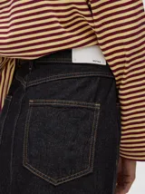 Falda midi de denim color marrón con hilado a la vista en el ruedo y abotonadura frontal.