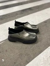 Zapato tipo mocasín color peltre con detalle de costuras en contraste y suela track color negro.